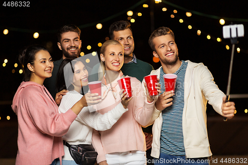 Image of friends with drinks taking selfie at rooftop party