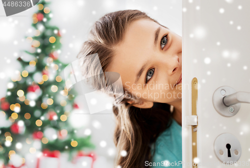 Image of happy girl looking out open door on christmas