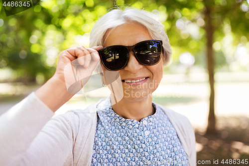 Image of portrait of happy senior woman at summer park