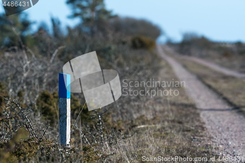 Image of Way marker by an unfocused dirt road