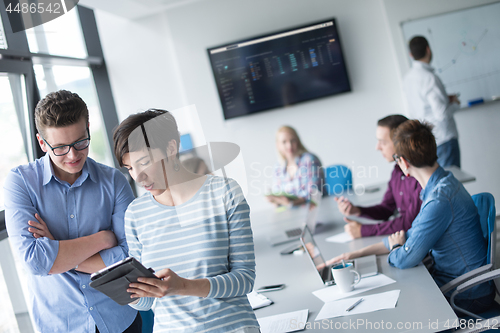 Image of Two Business People Working With Tablet in office