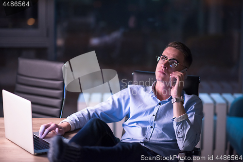 Image of businessman using mobile phone in dark office