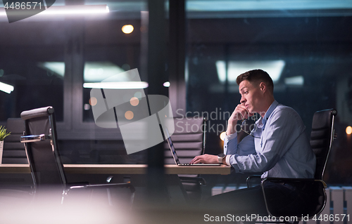 Image of man working on laptop in dark office