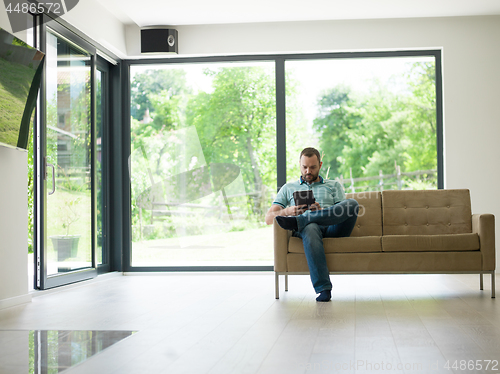 Image of man on sofa using tablet computer