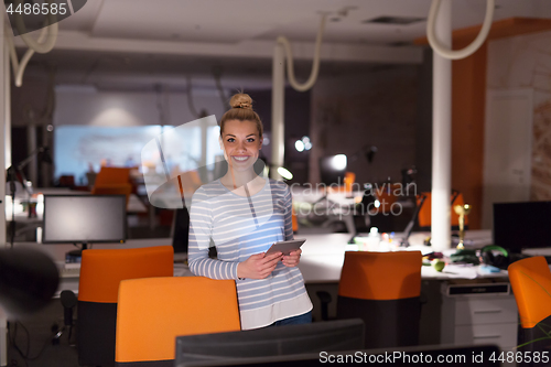 Image of woman working on digital tablet in night office