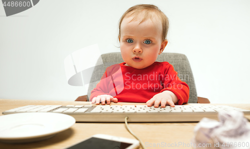 Image of Happy child baby girl toddler sitting with keyboard of computer isolated on a white background