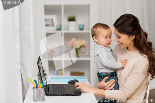 Image of happy mother with baby and laptop working at home