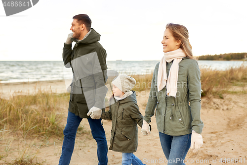 Image of happy family walking along autumn beach