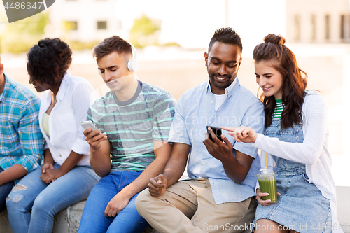 Image of friends with smartphones hanging out in summer