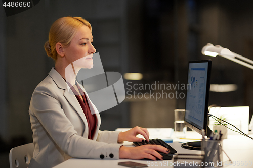 Image of businesswoman at computer working at night office