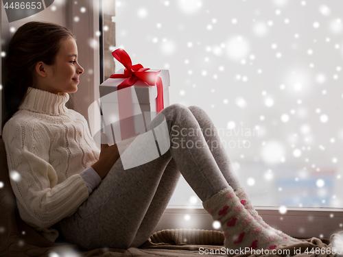 Image of girl with christmas gift sitting on sill at window