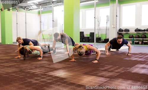 Image of group of people doing push-ups in gym