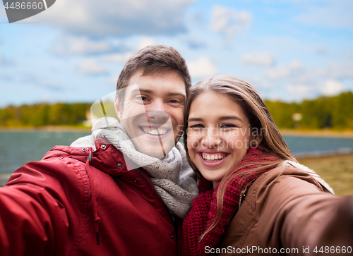 Image of happy young couple taking selfie on autumn beach