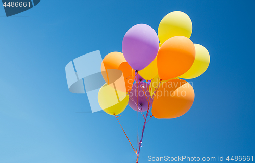 Image of close up of colorful helium balloons in blue sky