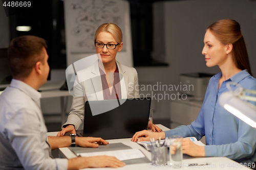 Image of business team with laptop working at night office