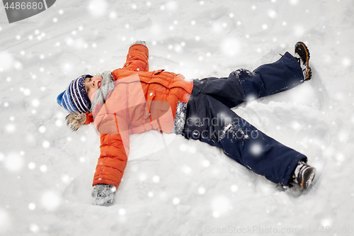 Image of happy little boy making snow angels in winter