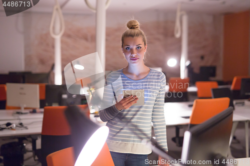 Image of woman working on digital tablet in night office