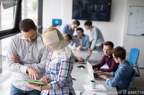 Image of Two Business People Working With Tablet in office