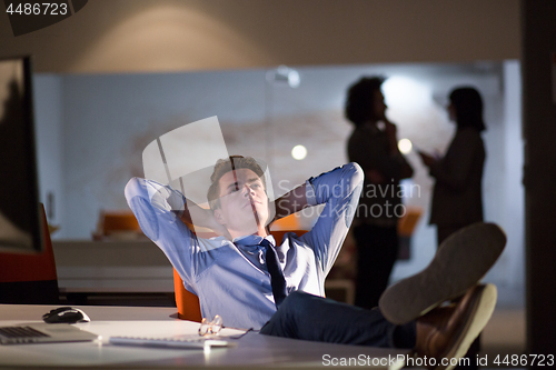 Image of businessman sitting with legs on desk at office