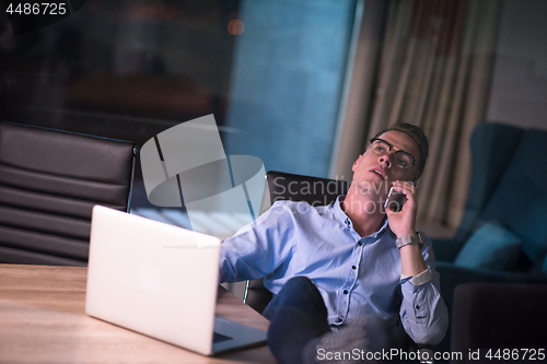 Image of businessman using mobile phone in dark office