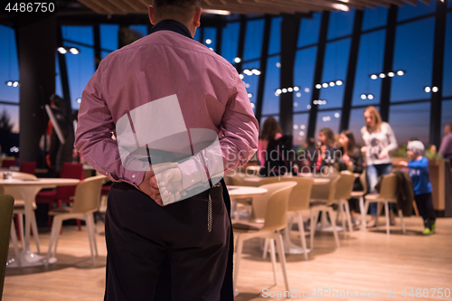 Image of waiter standing with hands behind his back