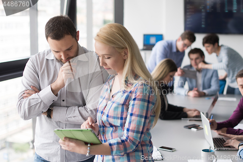 Image of Two Business People Working With Tablet in office