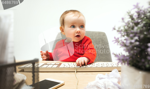 Image of Happy child baby girl toddler sitting with keyboard of computer isolated on a white background