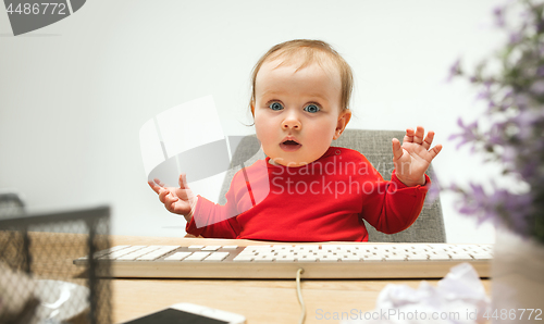 Image of Happy child baby girl toddler sitting with keyboard of computer isolated on a white background