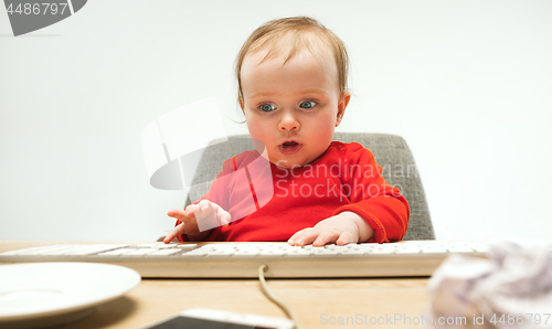 Image of Happy child baby girl toddler sitting with keyboard of computer isolated on a white background