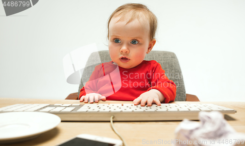 Image of Happy child baby girl toddler sitting with keyboard of computer isolated on a white background