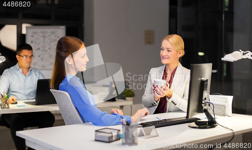 Image of businesswomen drinking coffee at night office