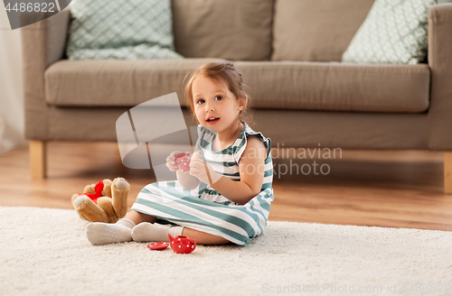 Image of little girl playing with toy tea set at home