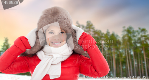 Image of happy woman in fur hat over winter forest