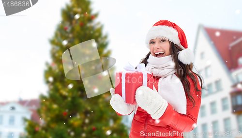 Image of happy woman with gift over christmas tree