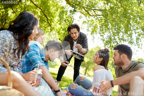 Image of friends with drinks and food at picnic in park