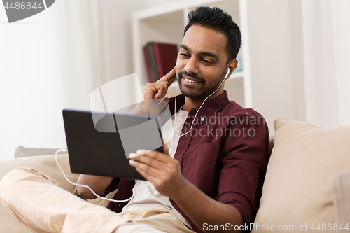 Image of man in earphones with tablet pc listening to music