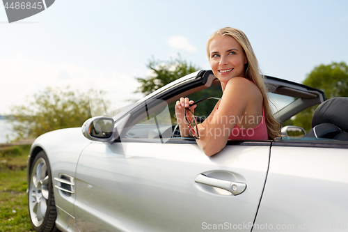 Image of happy young woman in convertible car