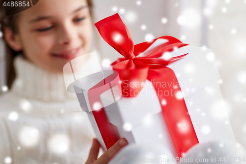 Image of girl with christmas gift sitting on sill at home