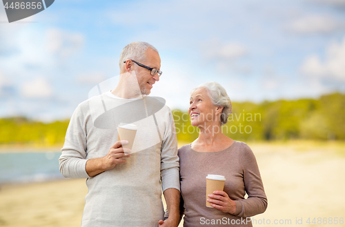 Image of senior couple with takeaway coffee on beach