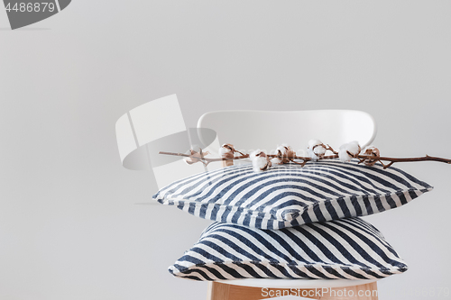 Image of Striped cushions and cotton branch on a chair