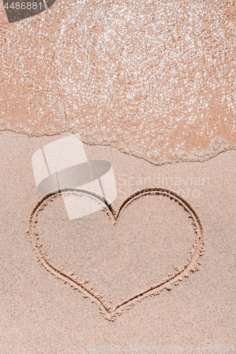 Image of Ocean wave and heart drawn on the sand