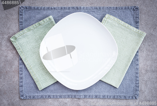 Image of White plate and linen textiles in pastel colors