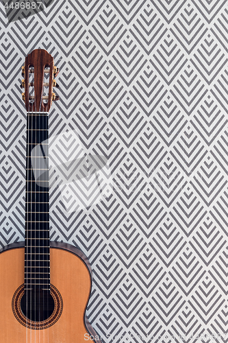 Image of Classical guitar near a wall with geometric wallpaper