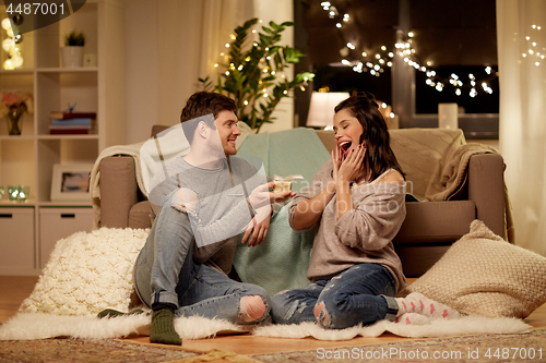 Image of happy couple with gift box at home