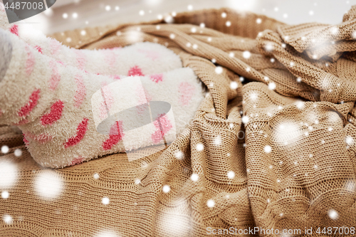 Image of female feet in socks and knitted plaid in winter