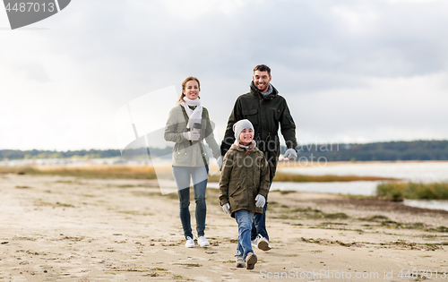 Image of happy family walking along autumn beach