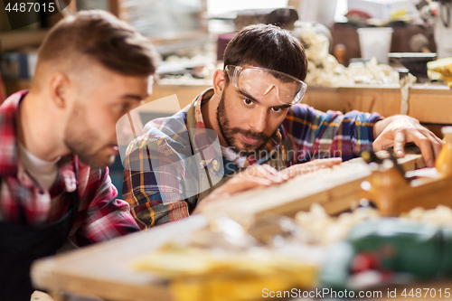 Image of carpenters measuring wooden board at workshop