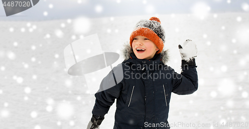 Image of happy boy playing and throwing snowball in winter