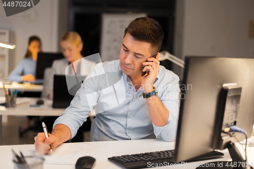 Image of man calling on smartphone at night office