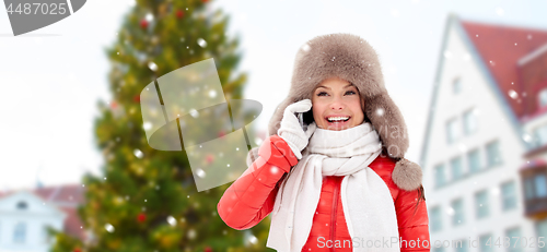 Image of woman calling on smartphone over christmas tree